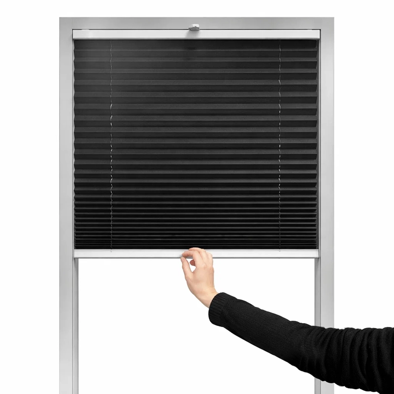 Ruka sťahuje plisé roletu zhora nadol pre nastavenie tienenia na okne.