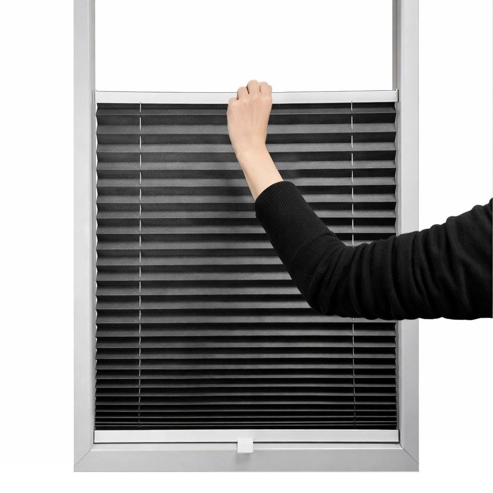 Ruka posúva plisé roletu zdola nahor pre reguláciu svetla a súkromia.