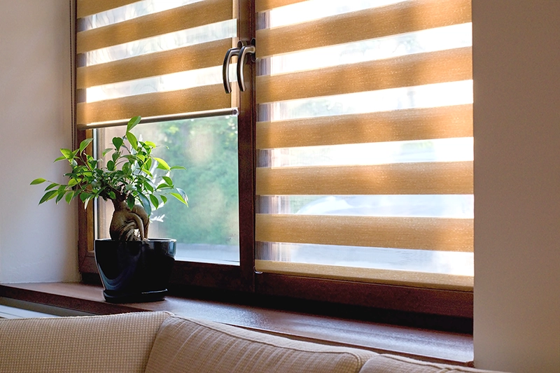 Moderná roleta upevnená na drevenom okne tlmí ostré slnko z exteriéru