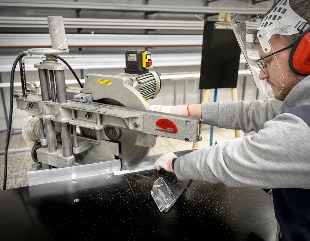 Pracovník reže materiál na výrobu sietí proti hmyzu popri prehľade typov sieťoviny – sivá, čierna a odolná PET